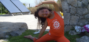 Crinaça de 3 anos a praticar Yoga em lateroflexão a sorrir.